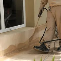 General pest control technician spraying exterior perimeter around a home in Boulder, CO