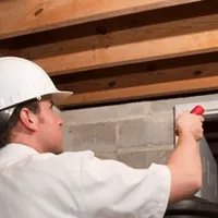 Termite inspection technician checking a basement wall and framing for termite activity in Boulder, CO